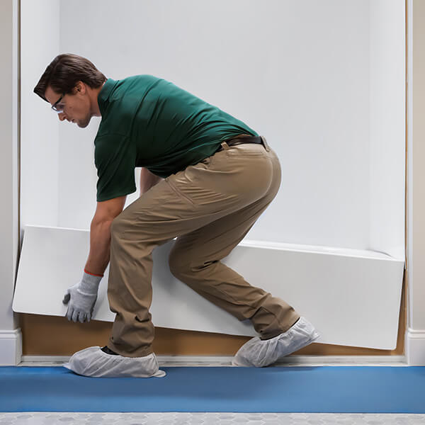 A Bath Fitter installer places a brand new acrylic tub, over an old existing tub.