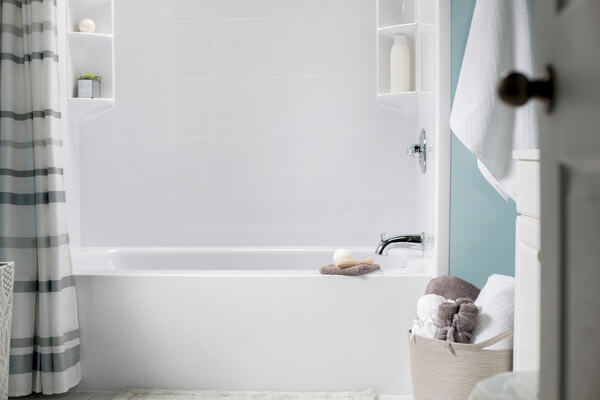 Opened door leading to bright white bathtub