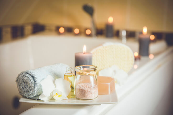 White ceramic tray with home spa supplies on top of a tub