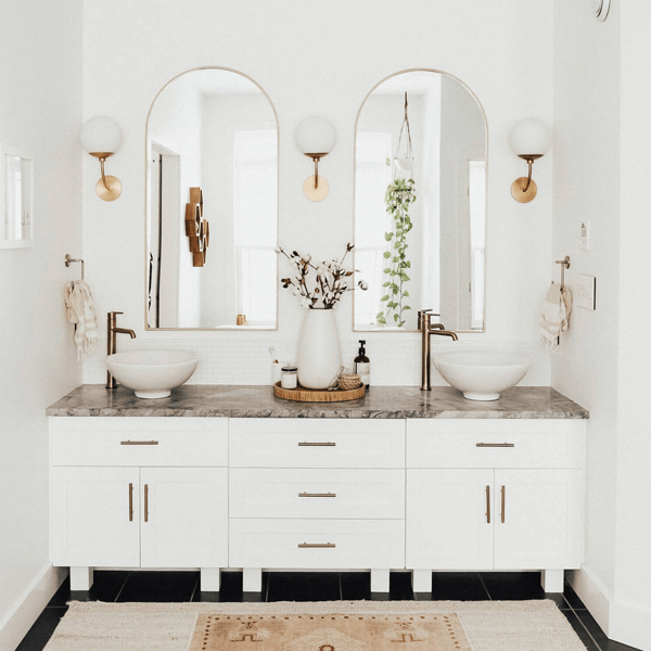 Gatsby inspired glamourous bathroom with art deco style bronze faucets and double mirrors