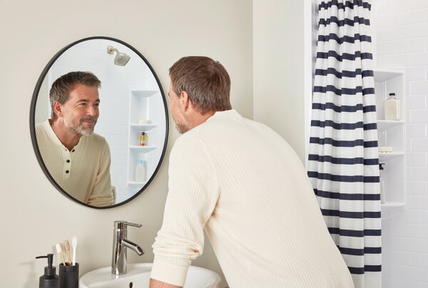 Man looking at himself through a round bathroom mirror