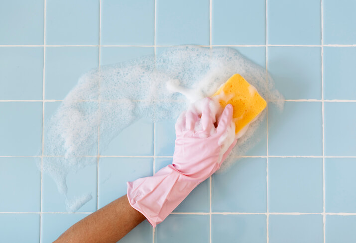 How to clean bathroom walls: Sponge and cleaning product on tiled bathroom wall