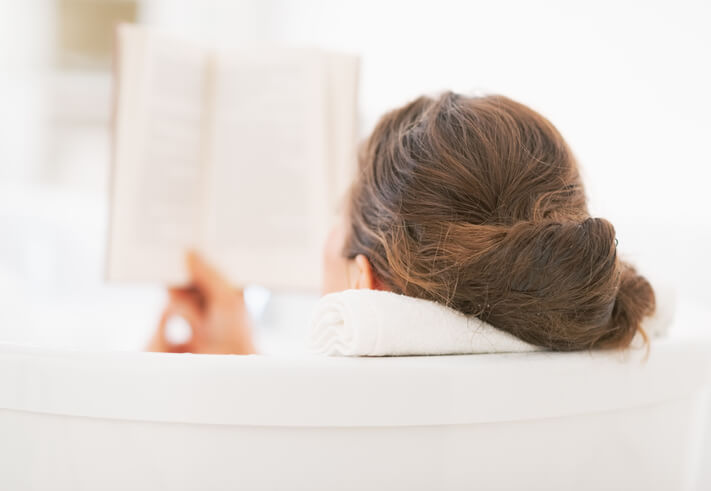 Woman in a bathtub reading a book