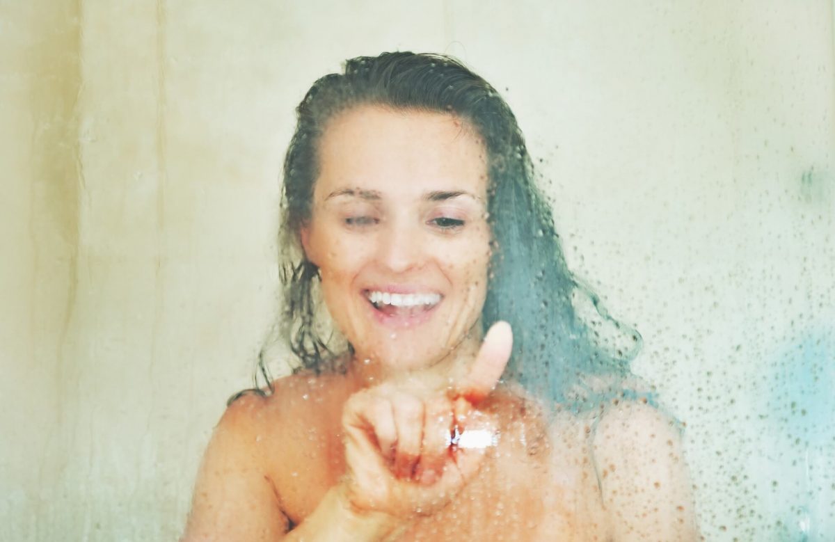 Woman pressing her finger on misty shower glass