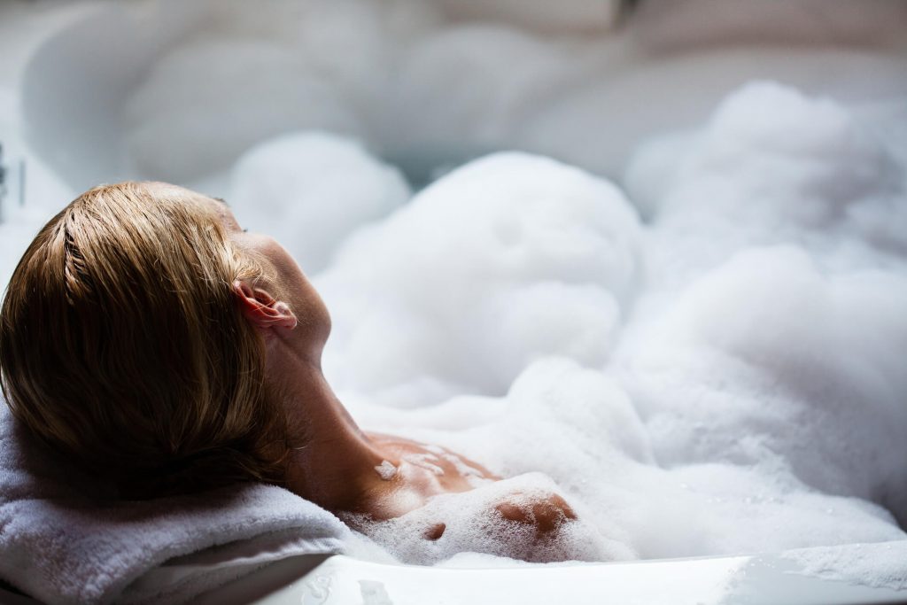 Young woman relaxing in a bath full of foam