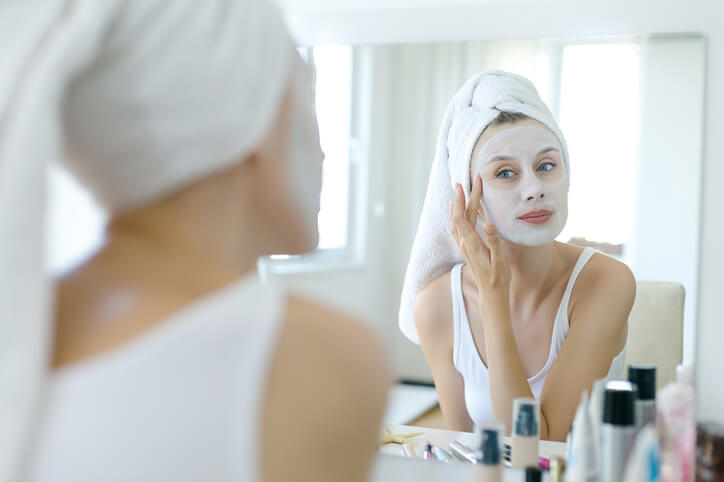 Woman with a face mask in front of mirror