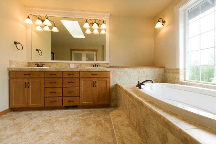 bathroom with travertine floor and a brown wooden vanity