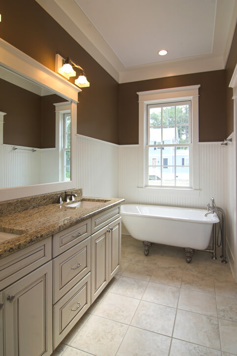 brown painted bathroom with white wainscot and crown molding