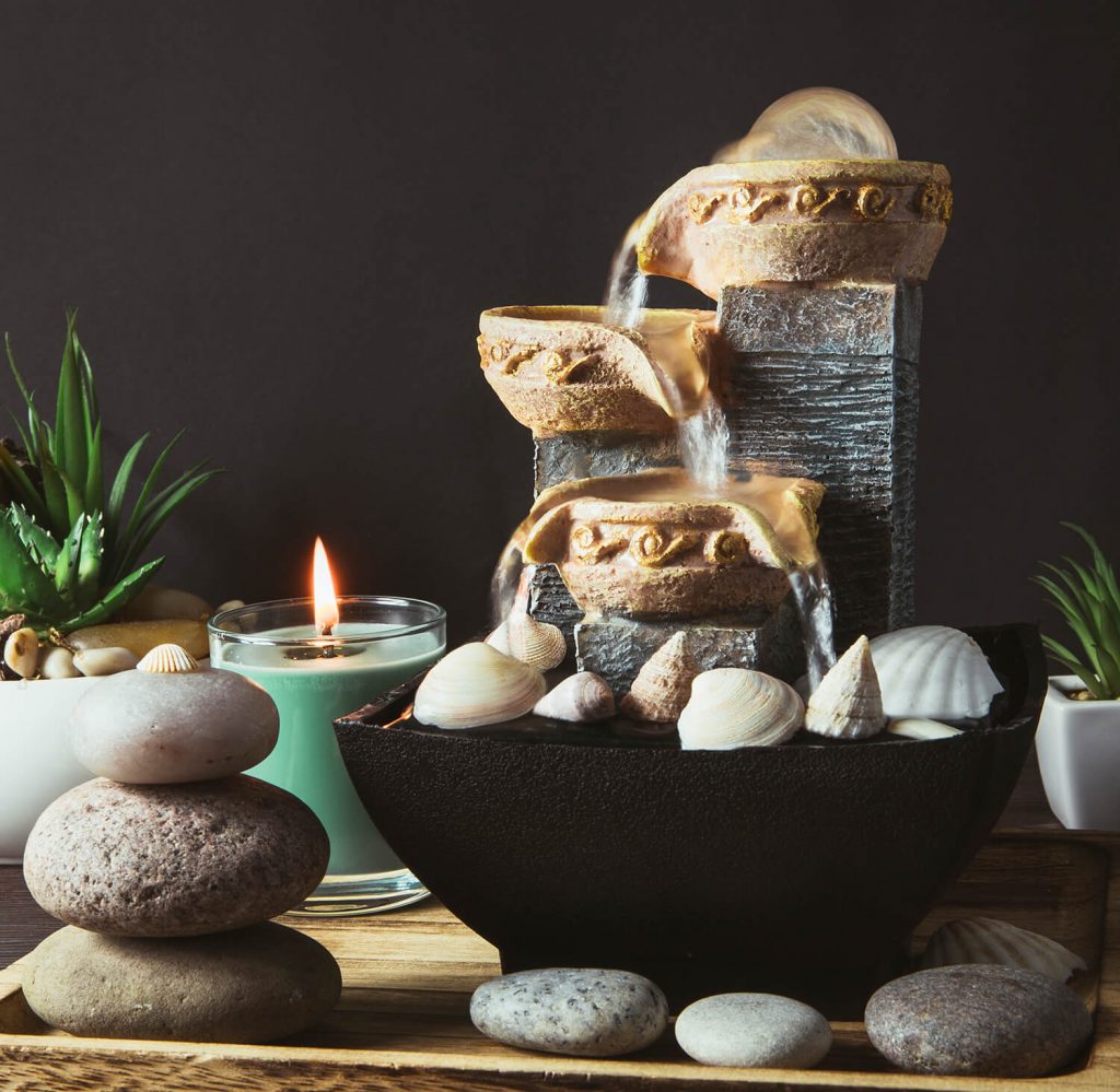 Small fountain with rocks, plants and candle