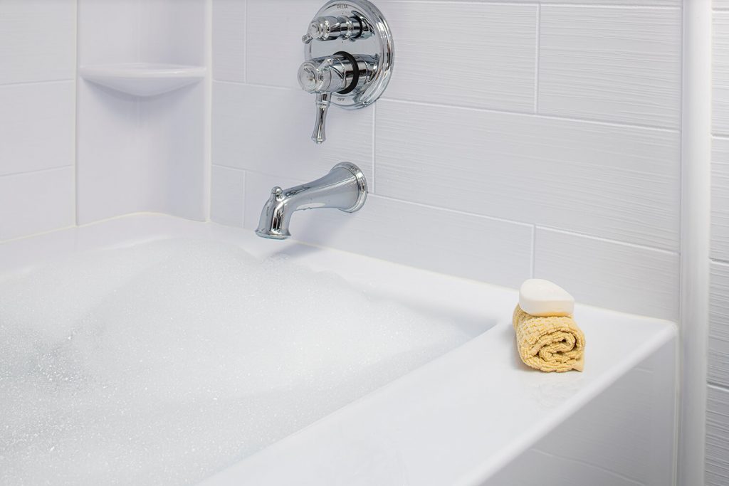 a close up of a bath fitter tub and seamless wall tile with face cloth and soap on ledge