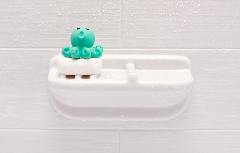 a turquoise bath toy and bar of soap sit on a soap holder