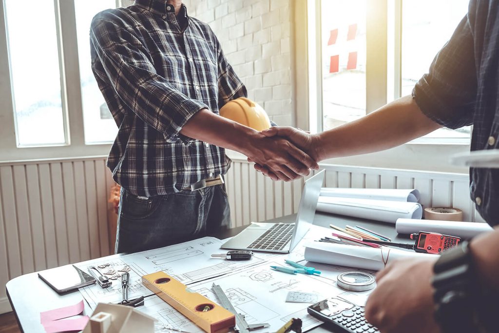 A man in a blue shirt shakes the hand of a contractor in agreement