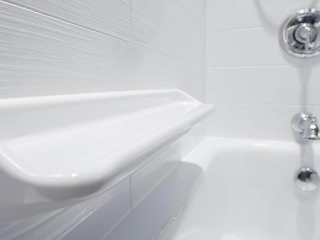 A close up of a chrome shower head and faucet with grab bar and shelves