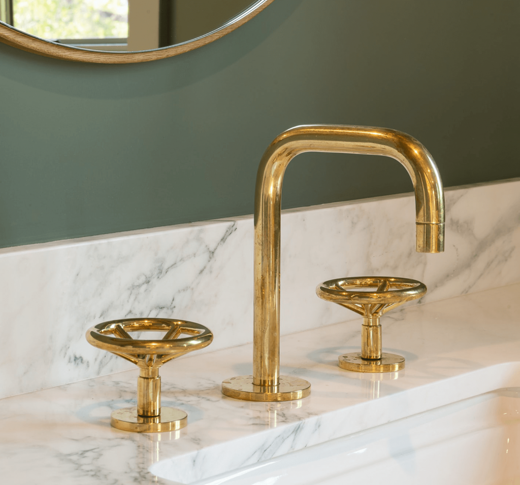 Beautiful gold faucet is installed on a white marble bathroom sink