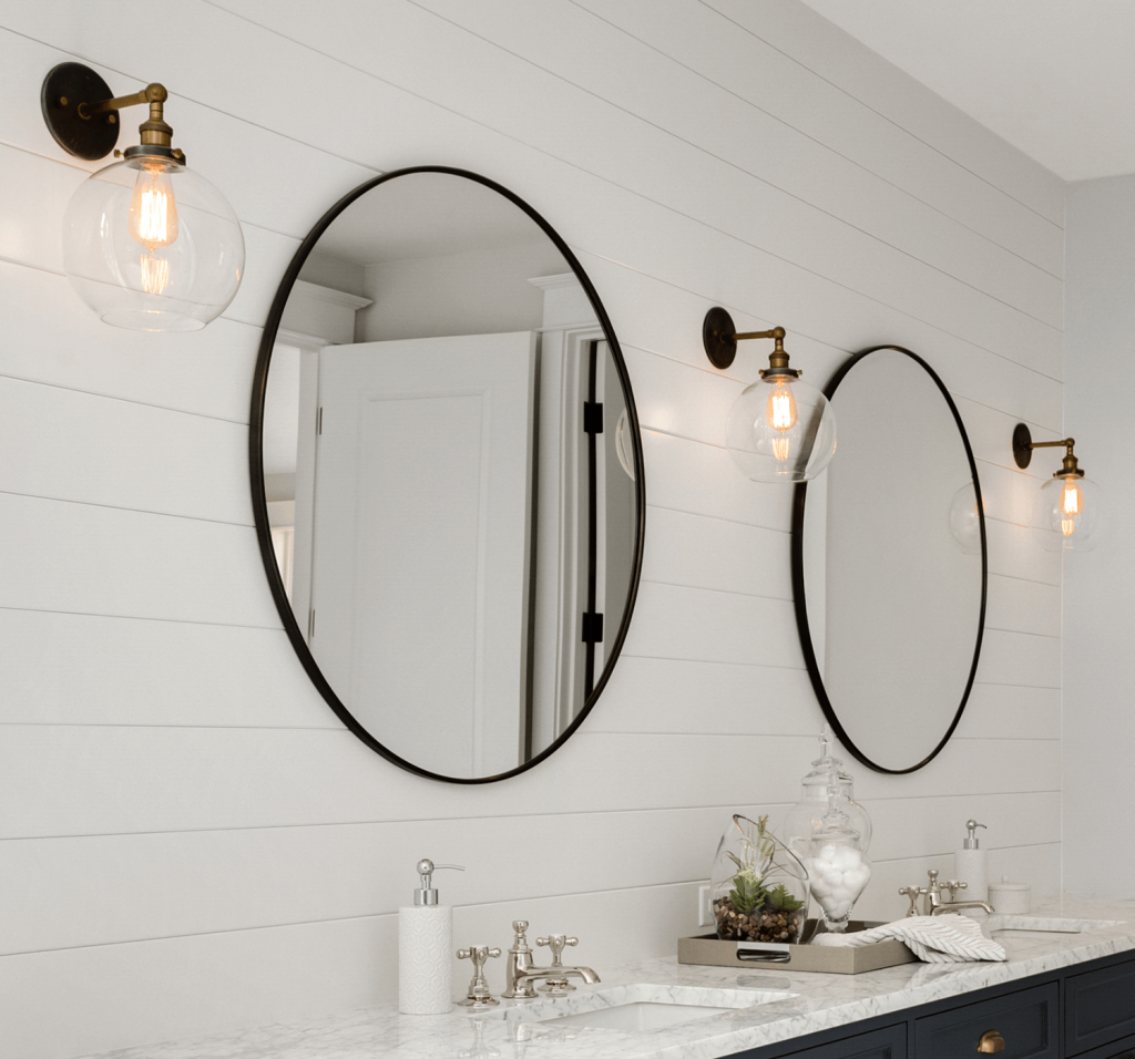 a stunning bathroom with dark blue cabinets and double vanity with two circular mirrors