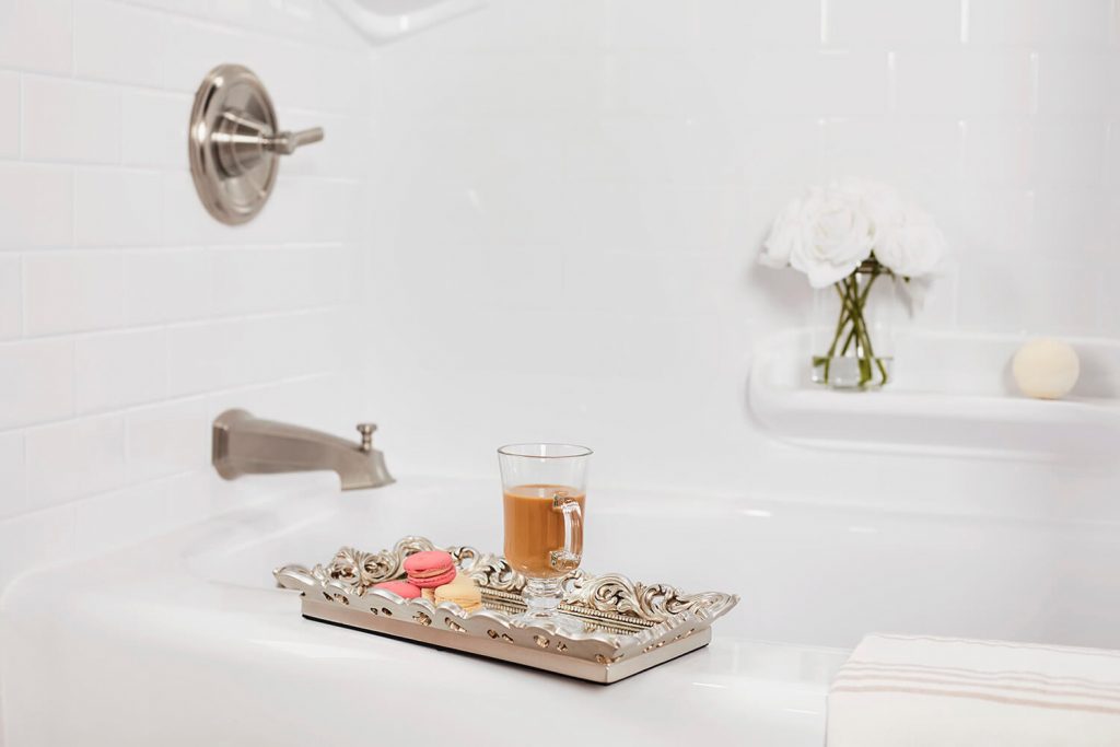 a silver tray adorned with a cup of coffee and macaroons sits on the ledge of a bathtub