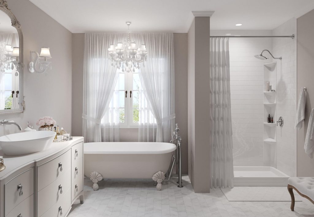 A clawfoot tub sits before a large double window with a lit chandelier majestically hanging above the tub.