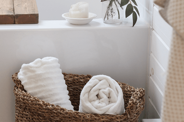 A serene scene in the bathroom with a wicker basket and two rolled up white towels inside