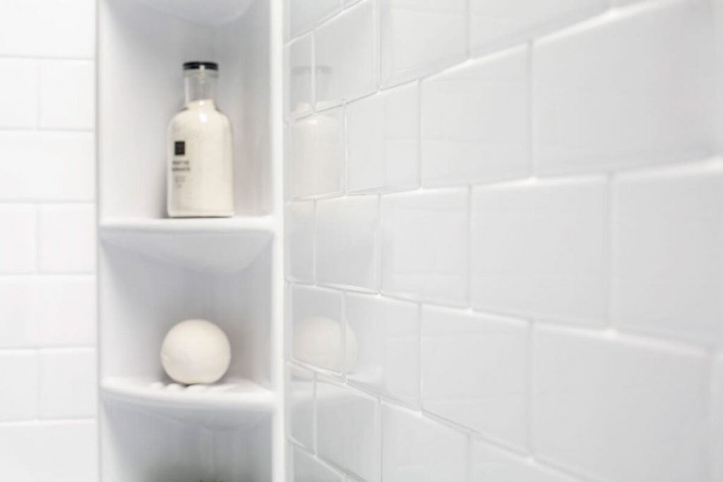 Soap and a bath bomb are on display on an acrylic shower shelf