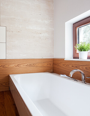 bathtub in a wood surround with large window along the length of the tub