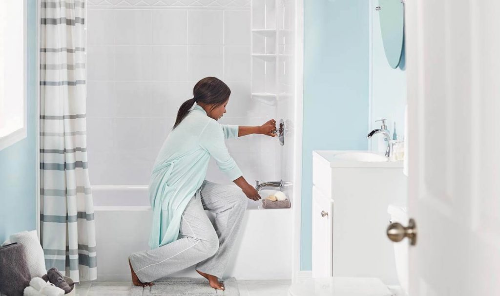 Woman adjusting bathtub faucets seated on bathtub edge