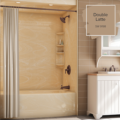 An ivory marlbe bathtub is the focus in a brown-tiled bathroom