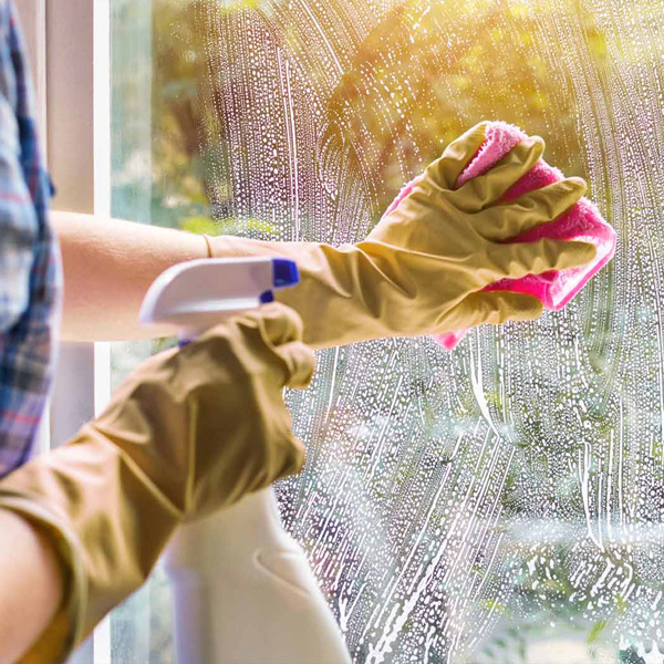 A woman is wiping down a soapy window